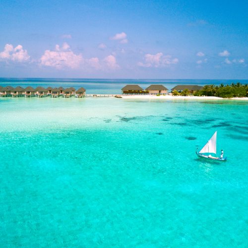 Traditional dhoni sailing past the overwater villas